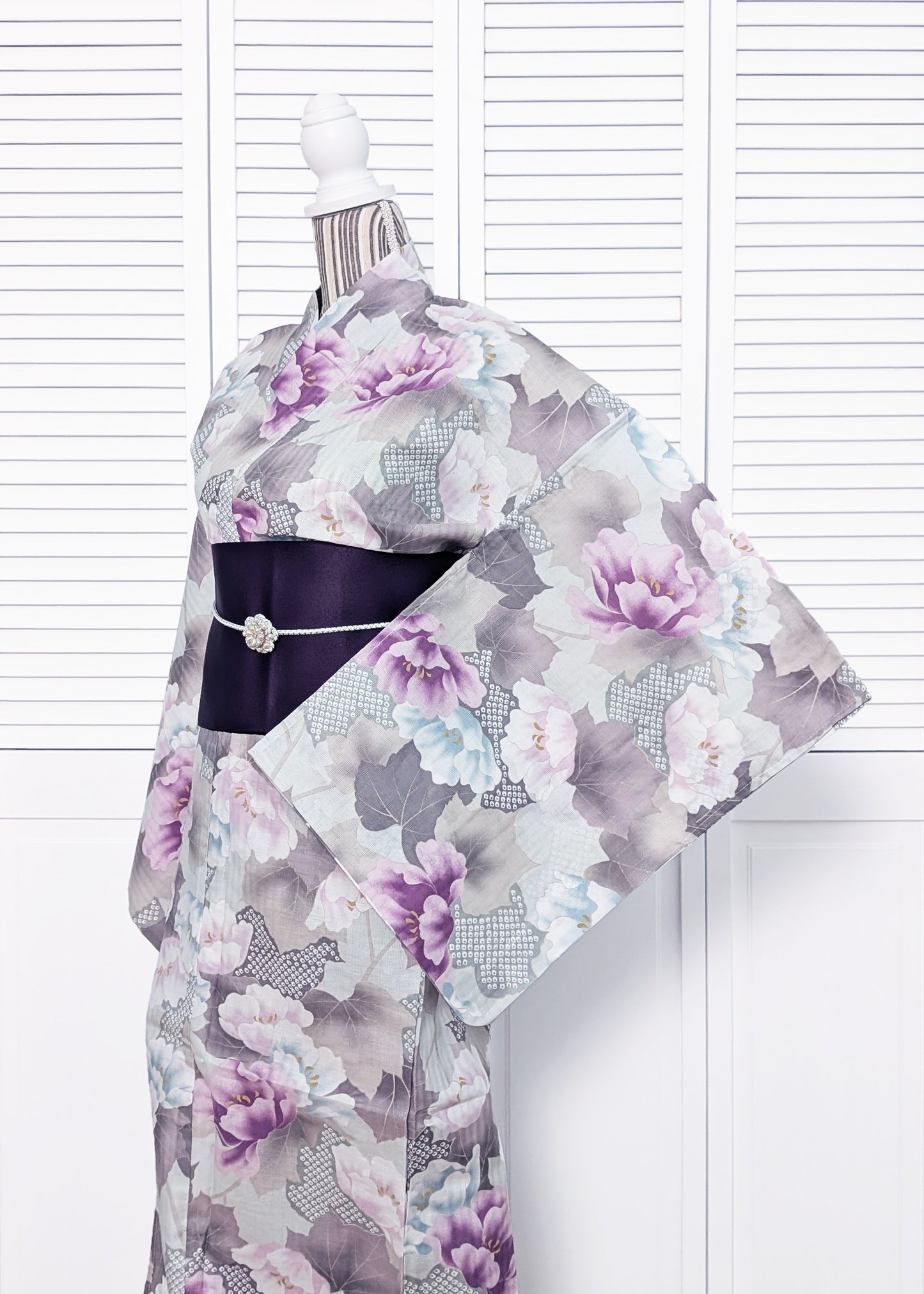 Floral kimono with a black belt on a mannequin against a white background