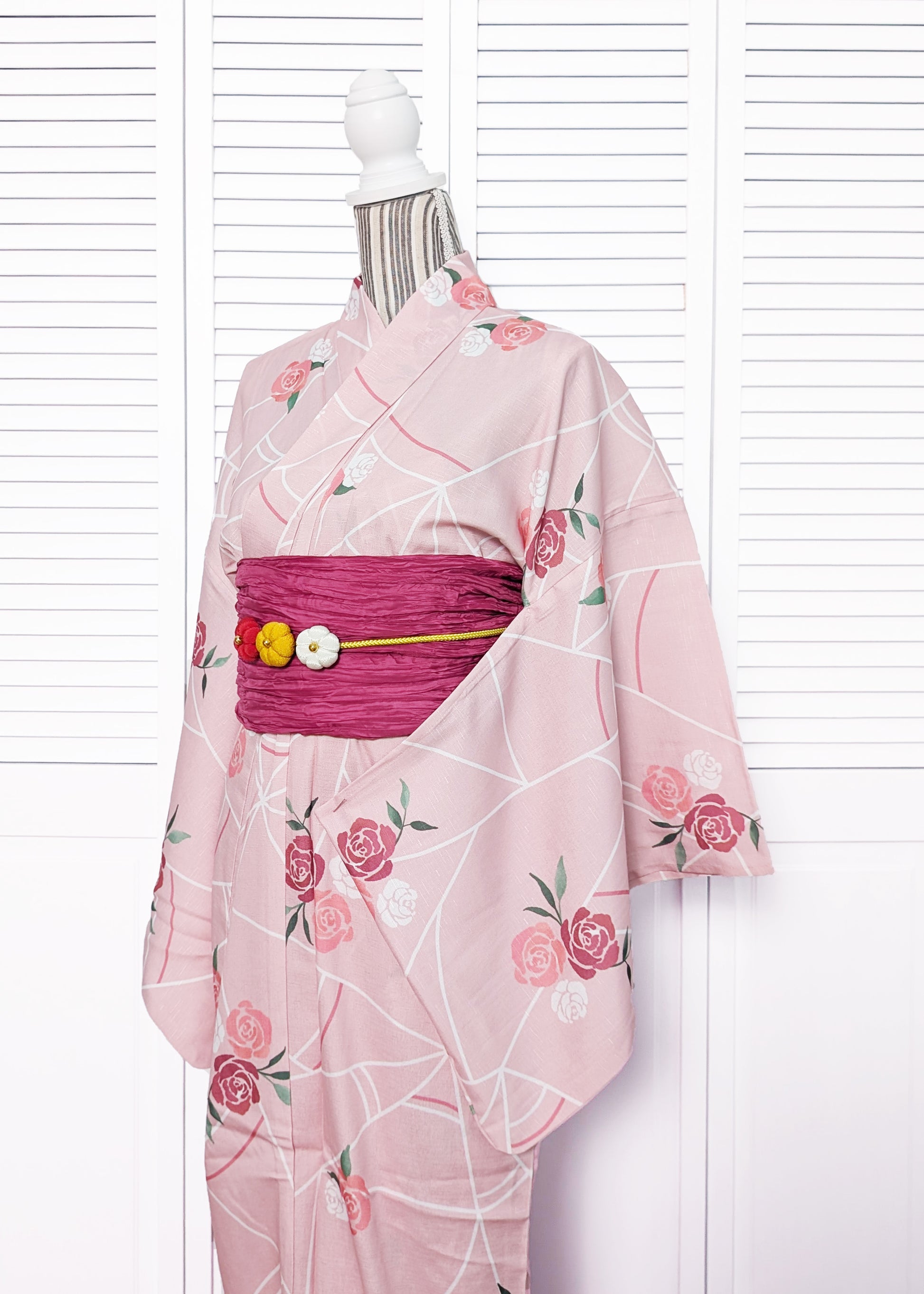 Pink yukata kimono with floral patterns on a mannequin against a white background