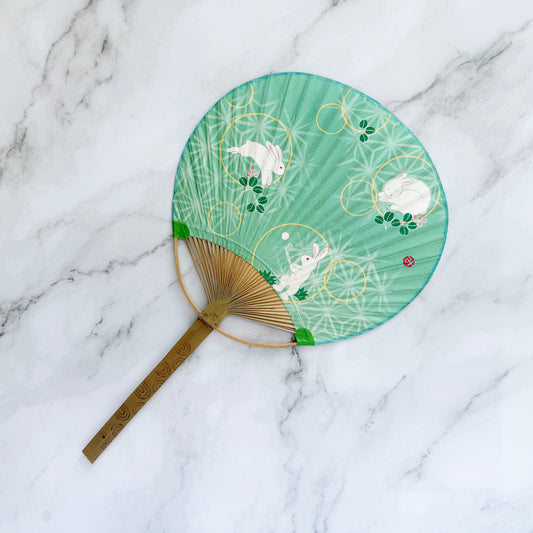 Decorative fan with rabbit design on a marble surface