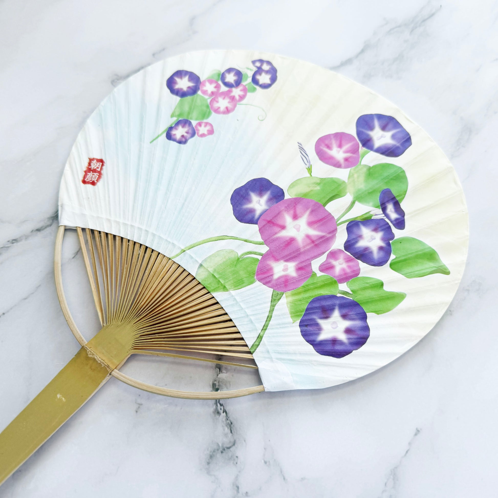 Handheld fan with floral design on a marble surface