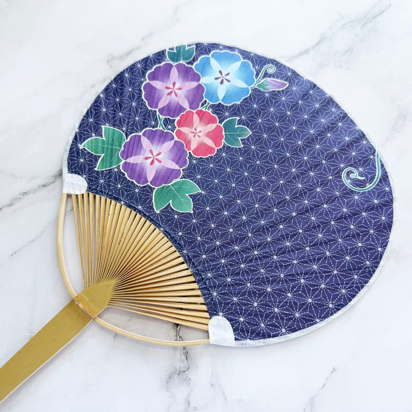 Handheld fan with floral design on a blue background