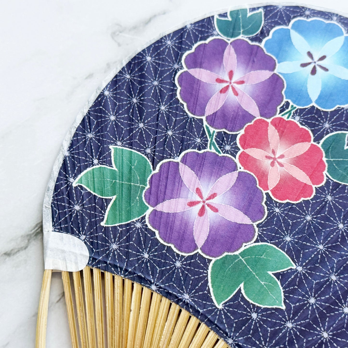 Handheld fan with floral design on a blue background