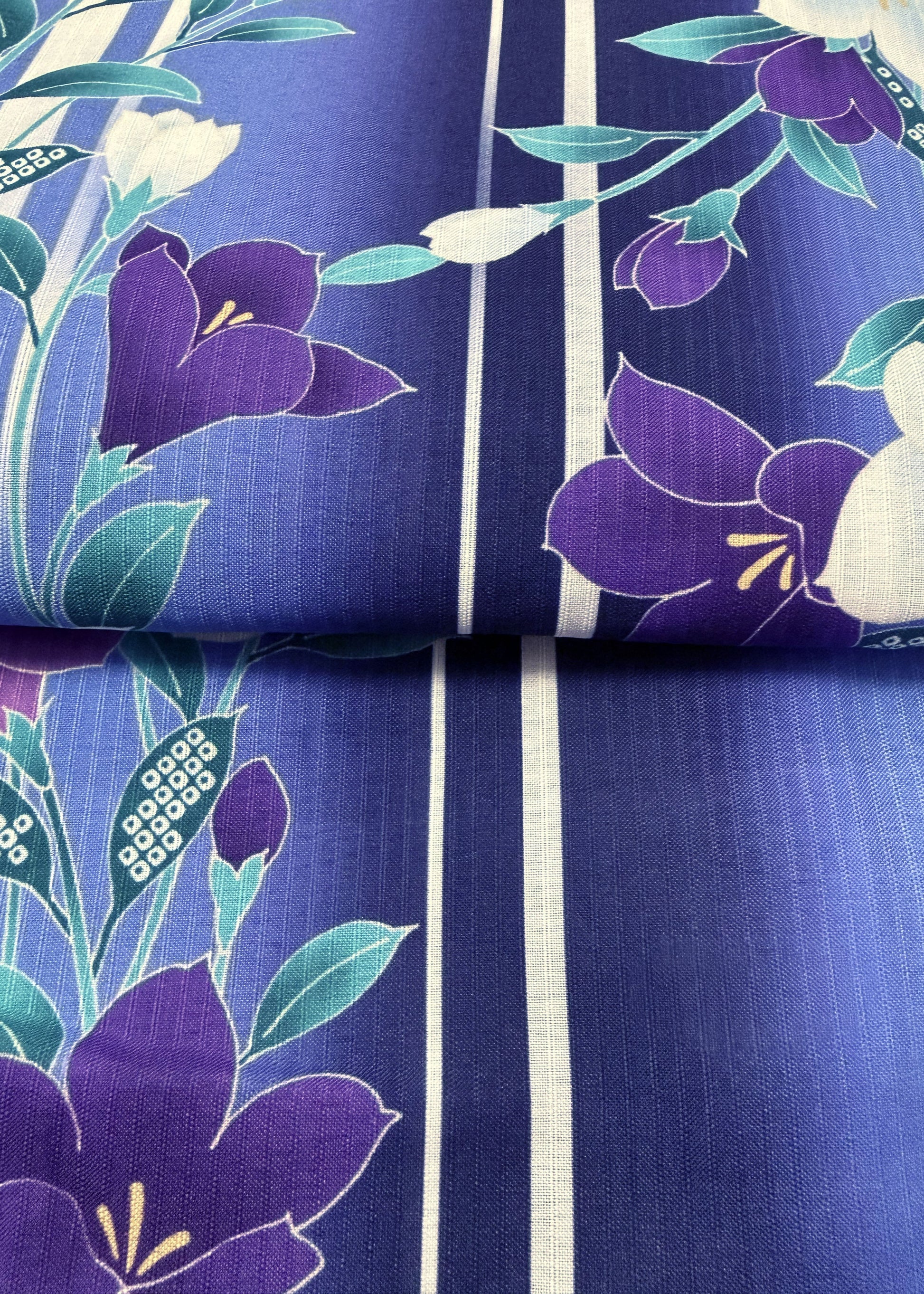 Floral fabric with purple flowers and green leaves on a blue background