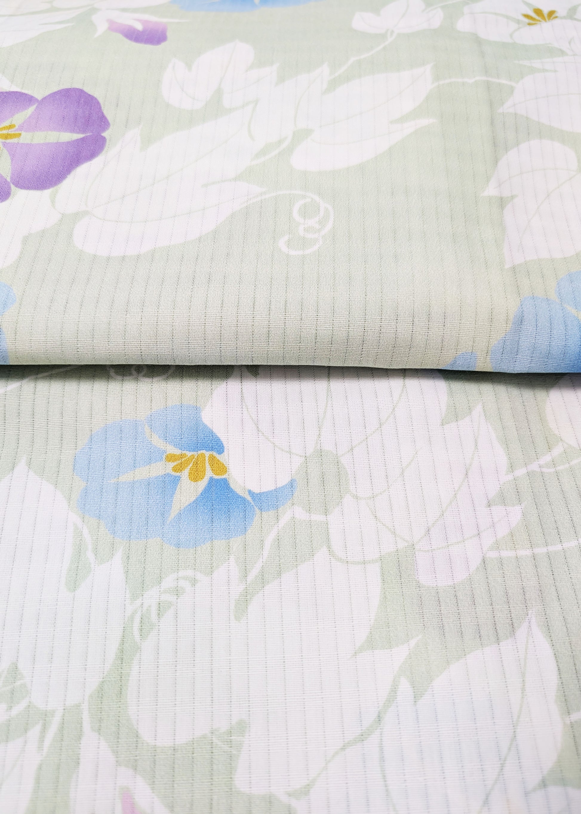 Floral patterned fabric with blue, purple, and white flowers on a light green background