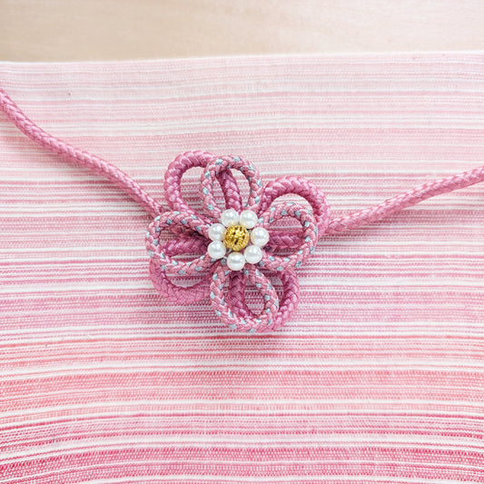 Pink waist string with a decorative flower on a pink textured background