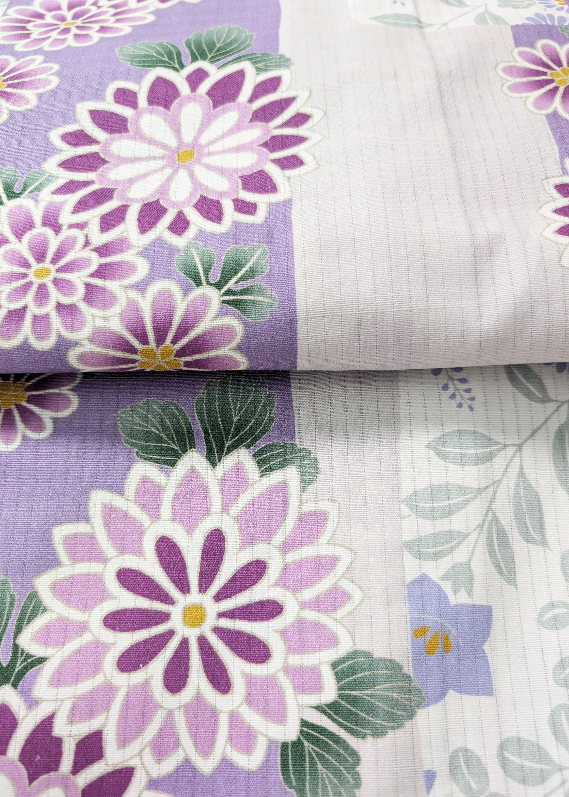 Floral fabric with purple flowers and green leaves on a purple background