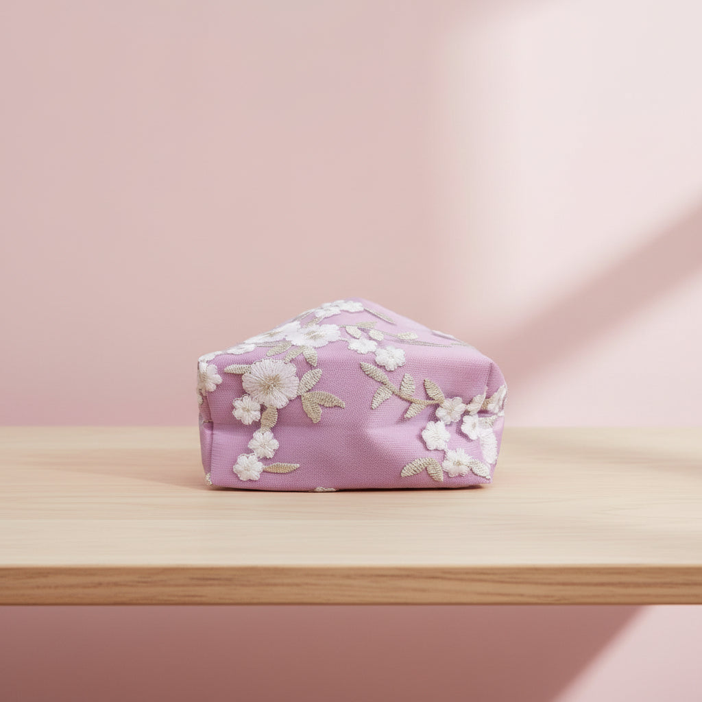 Floral-patterned pink pouch on a wooden surface with a soft pink background