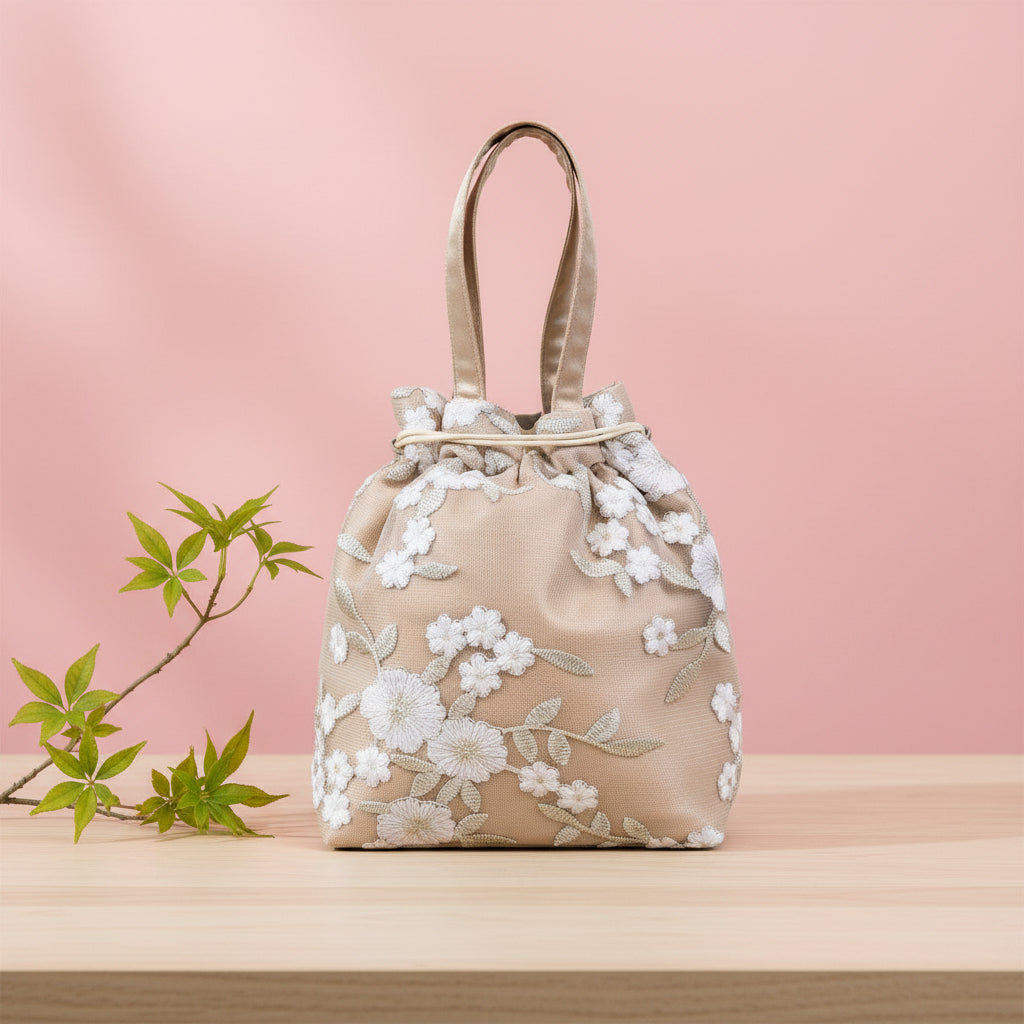 Beige handbag with white floral embroidery on a pink background