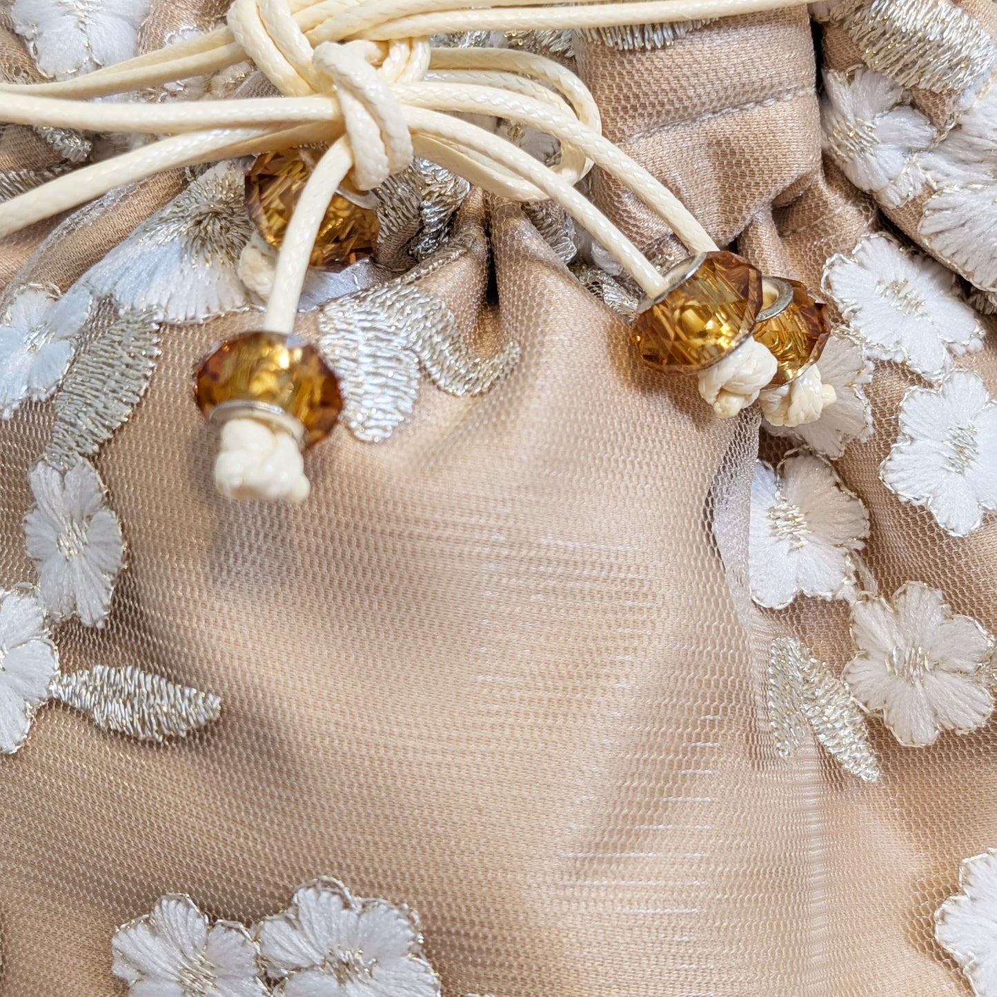Close-up of beige fabric with floral embroidery and amber beads