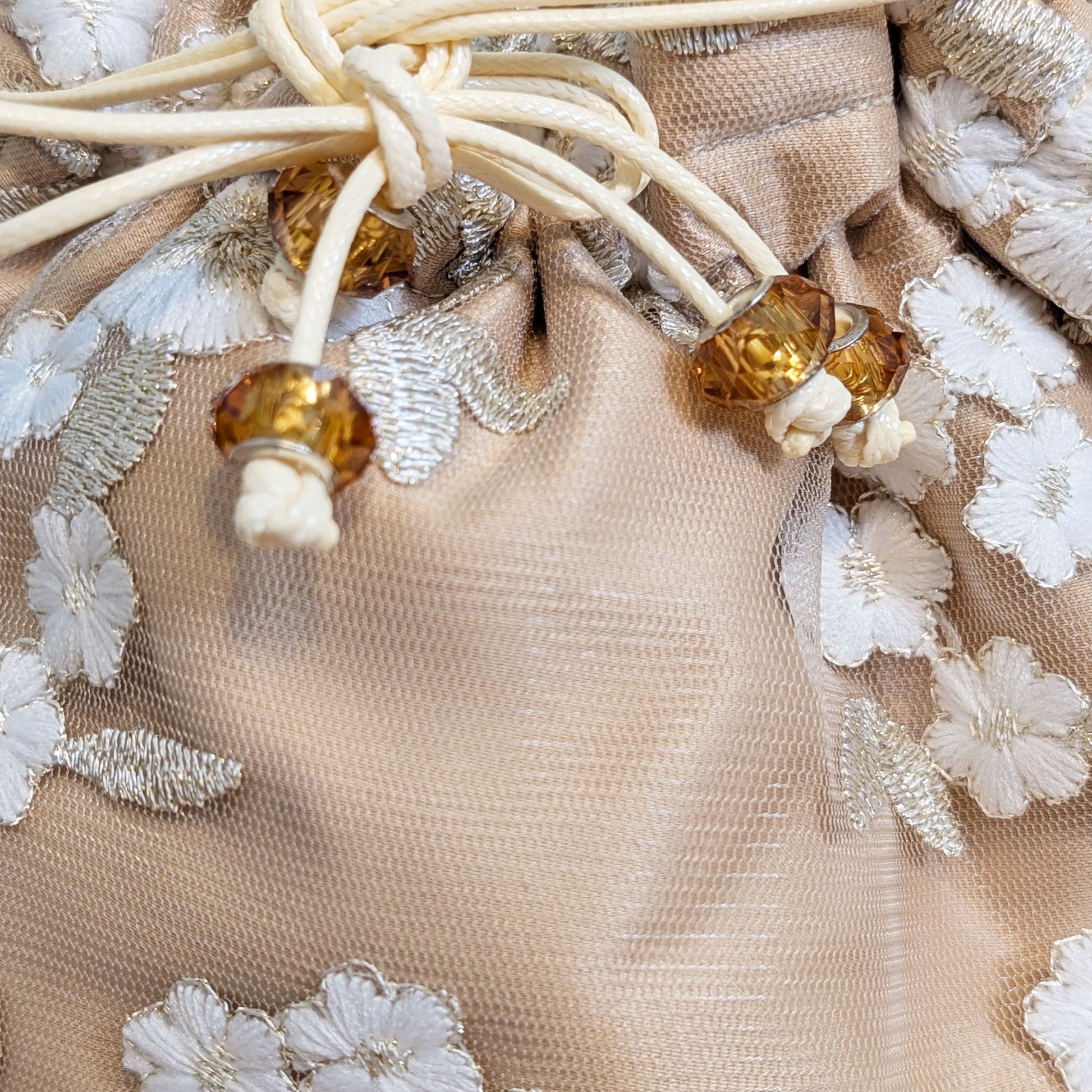 Close-up of beige fabric with floral embroidery and amber beads