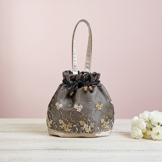 Embroidered handbag with floral patterns on a light pink background